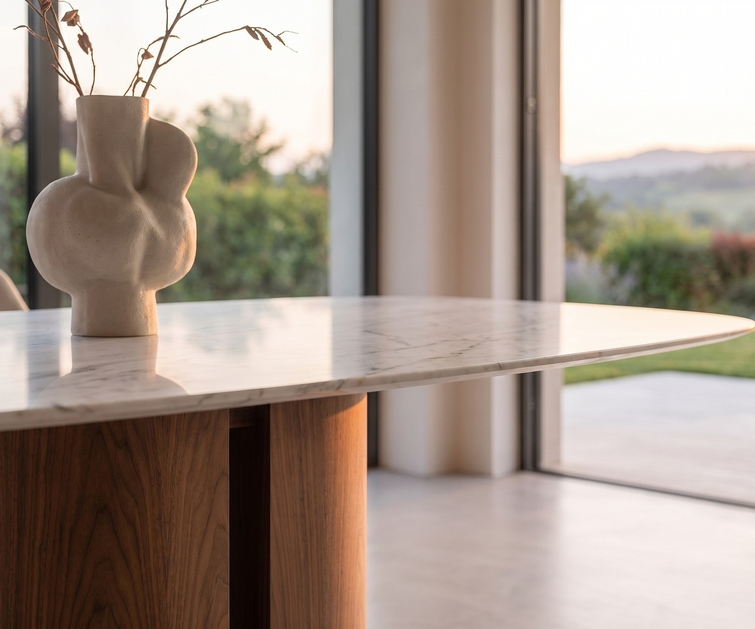 al2 el-it c 001 Esstisch mit Holzsockel & Marmor-Optik al2 el-it c 001 Esstisch im modernen Esszimmer mit weißer Marmor-Optik Platte, Holzsockel und Designer-Vase.