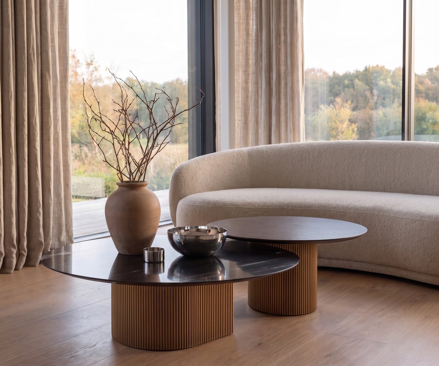 al2 dakry 006 Couchtisch-Set im modernen Wohnzimmer vor boucle Sofa mit gerilltem Holzfuß und runder Platte.