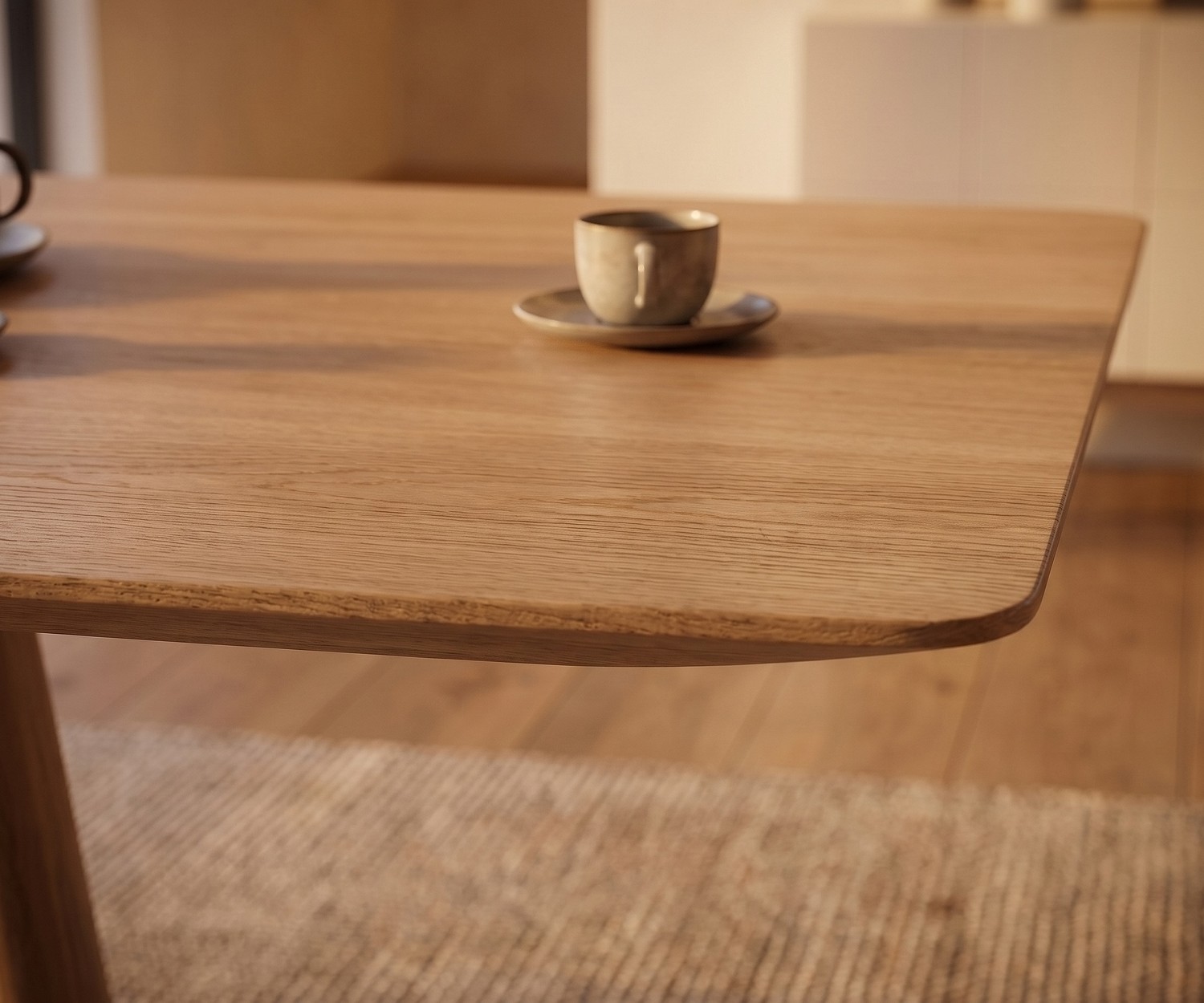 Esstisch mos-i-ko 001 a aus Eiche im Esszimmer, Nahaufnahme der abgerundeten Tischplatte mit Kaffeetasse, moderner Stil.