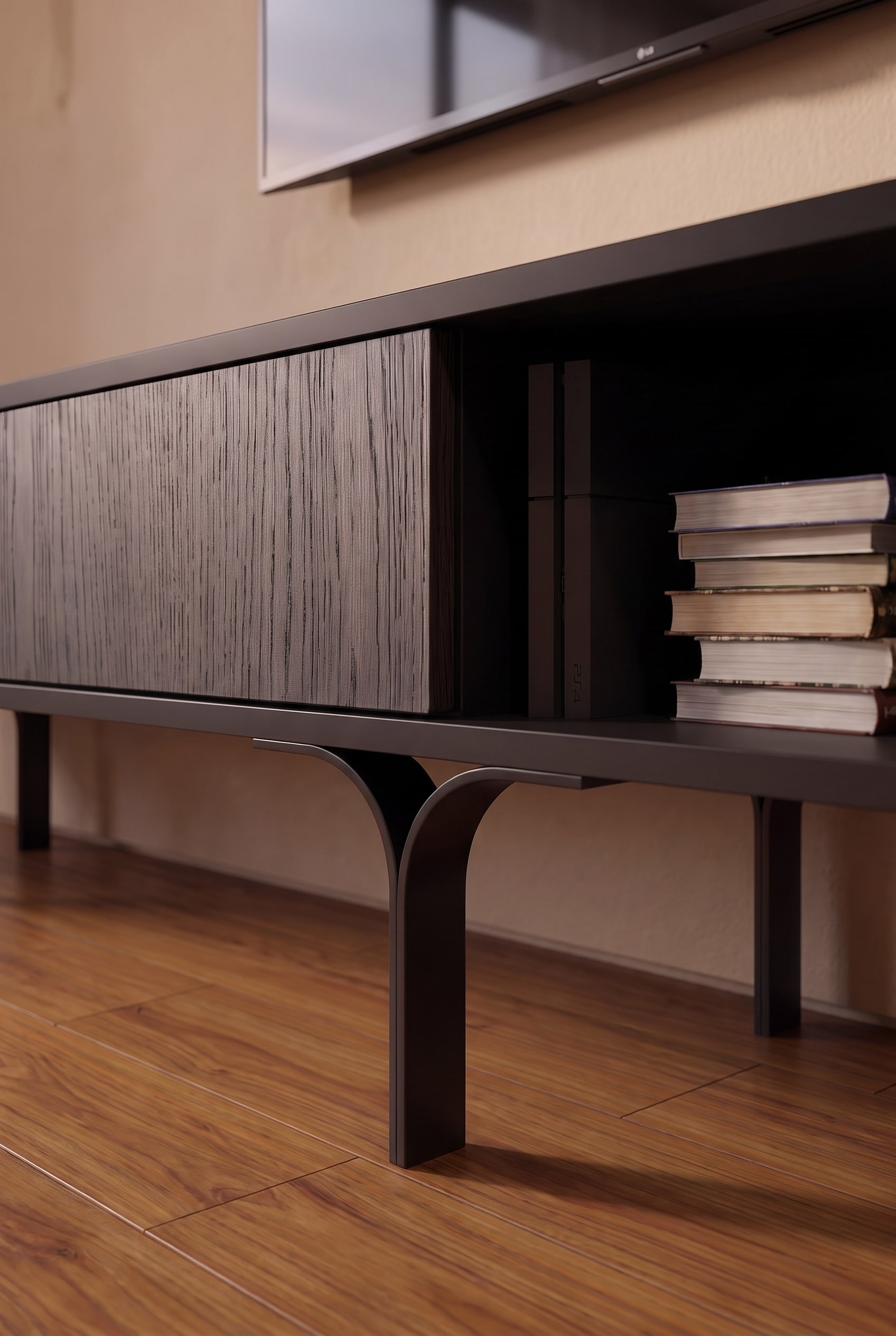 Detailaufnahme eines dunklen Lowboards mit strukturierter Holz-Schiebetür, Büchern und filigran gebogenen Metallfüßen.