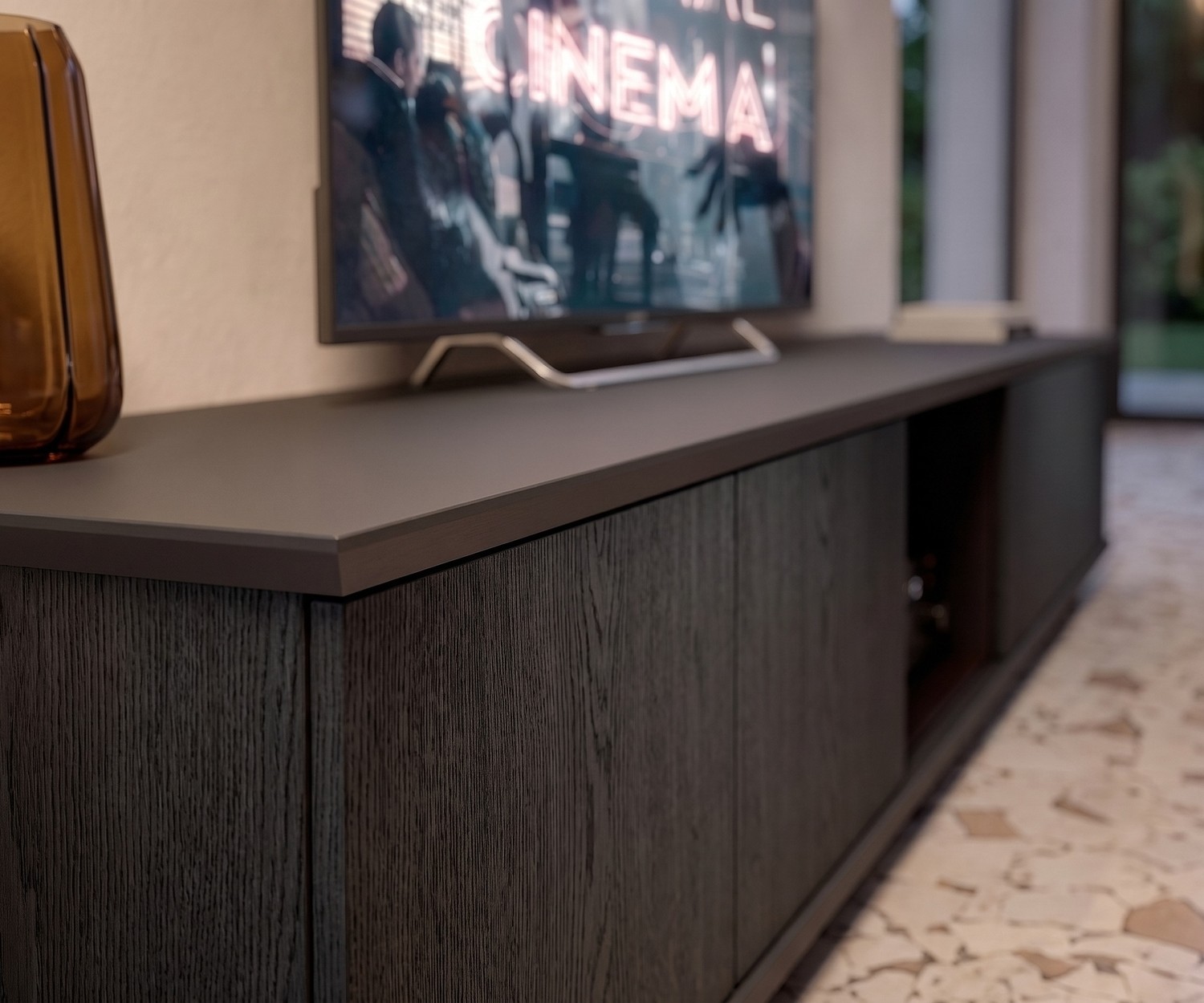 Ozzio Brera TV Lowboard in Eiche Schwarz Carbone mit matter Abdeckplatte im modernen Wohnzimmer neben Fernseher.