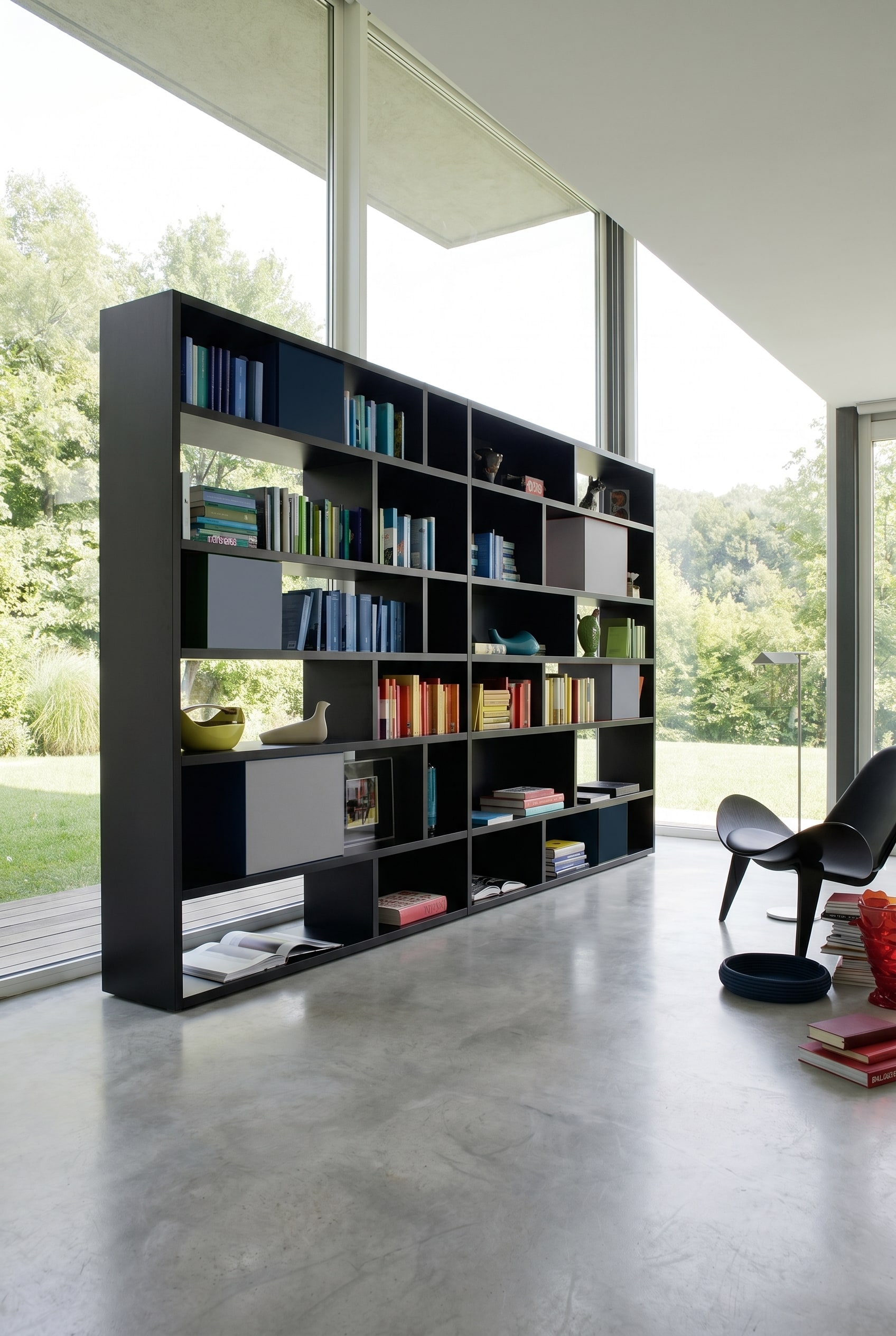 Mattschwarzes asymmetrisches Design-Regal mit integrierten grauen und blauen Aufbewahrungsboxen vor wei&szlig;en W&auml;nden