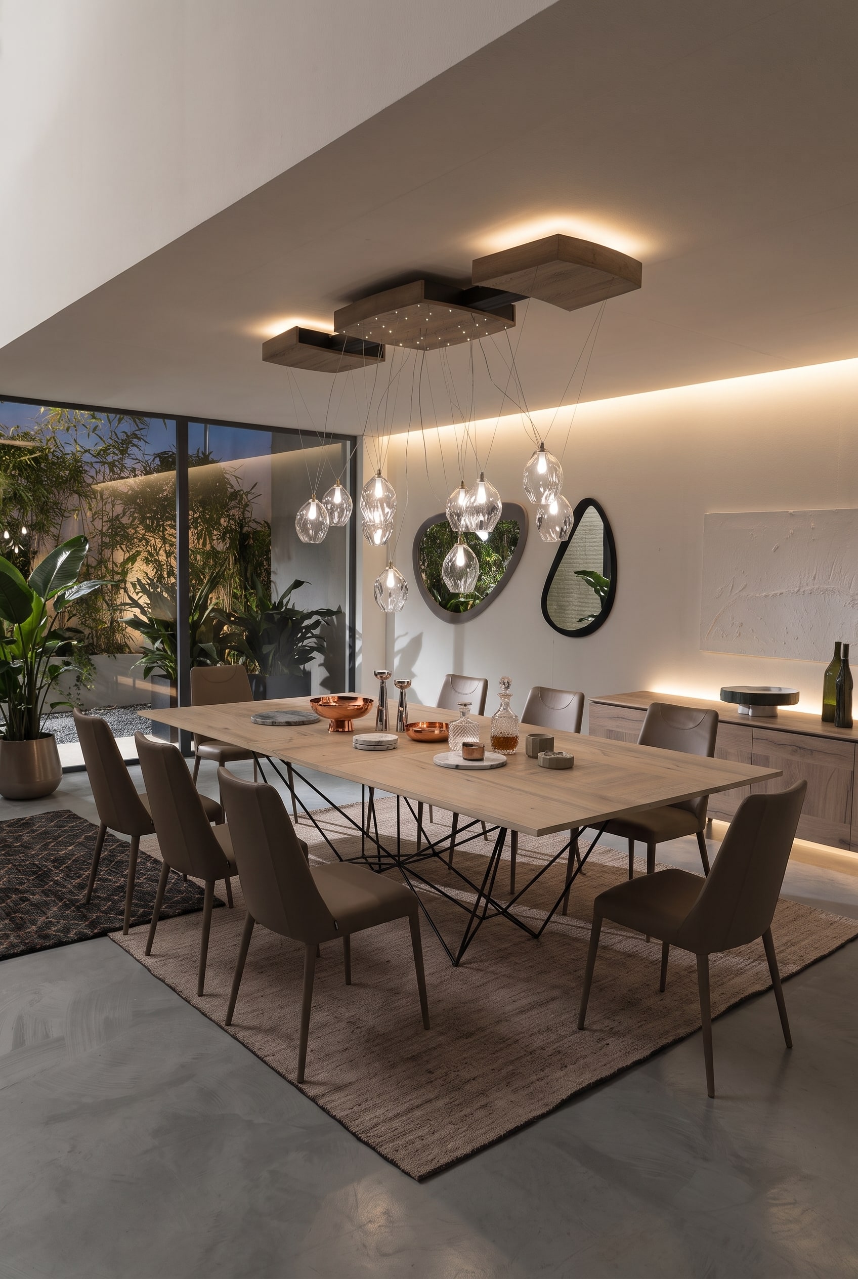 Modernes offenes Esszimmer mit großem Esstisch auf geometrischem Metallgestell, vier taupefarbenen Stühlen und Holz-Sideboard