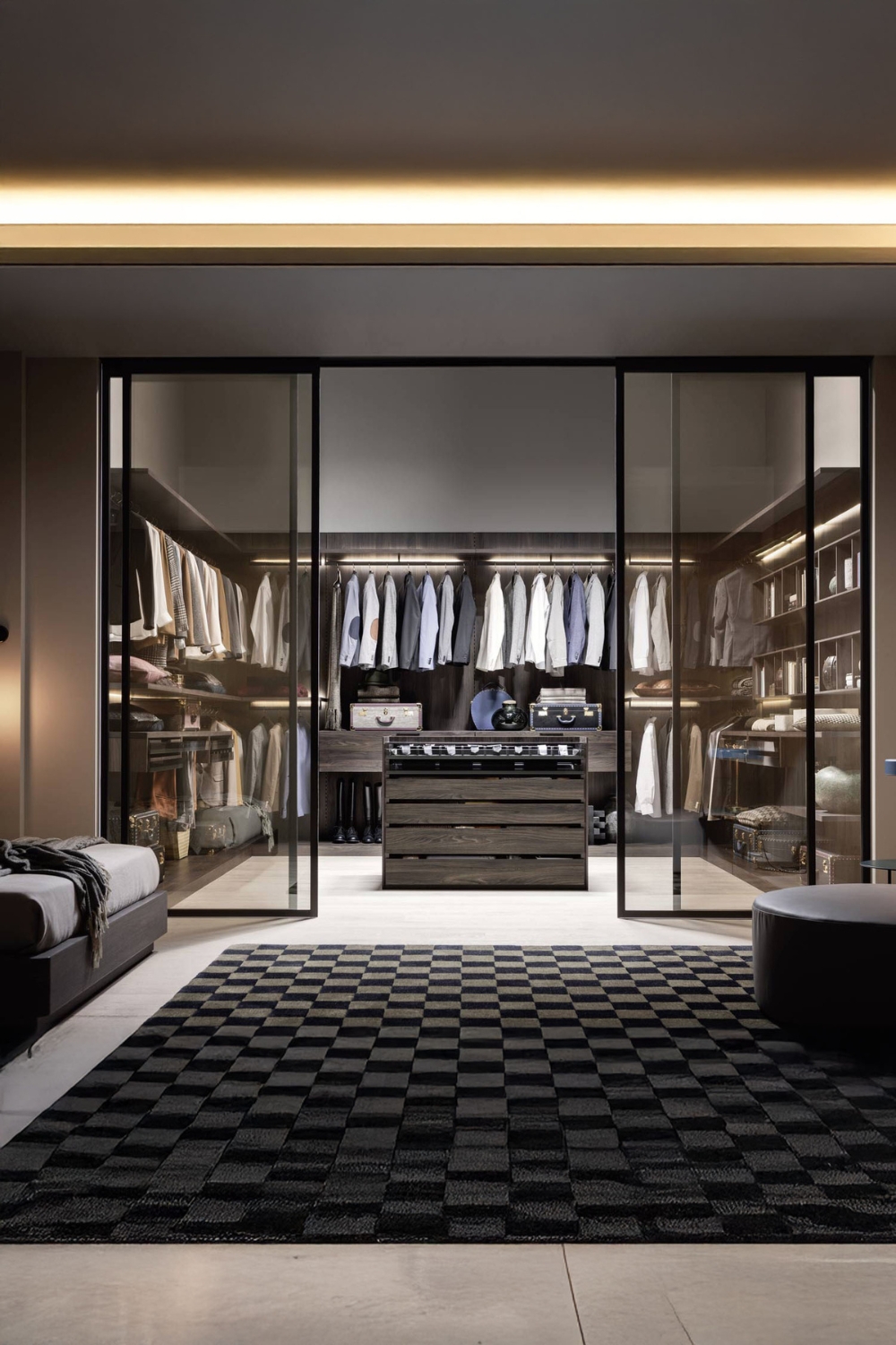 durch-glasschiebetueren-abgetrennter-begehbarer-kleiderschrank-mit-mittelinsel-in-holzoptik