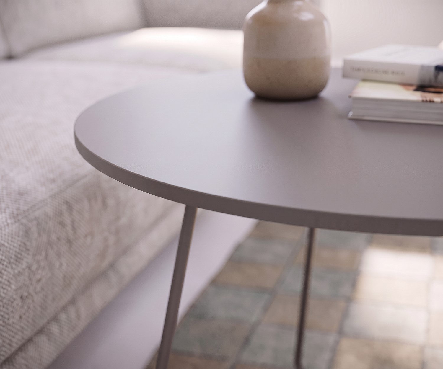 Couchtisch Orbis von Novamobili als Beistelltisch im Wohnzimmer am Sofa, runde Tischplatte in Mattgrau mit Vase.