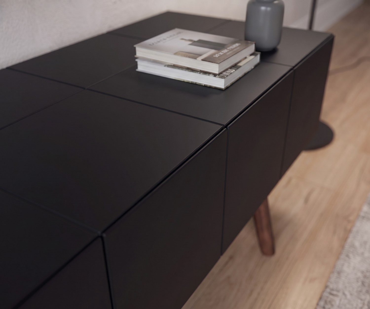 al2 Design Lowboard MOS-I-KO 005 B in Mattschwarz al2 TV Lowboard MOS-I-KO 005 B in Mattschwarz im Wohnzimmer, Detailaufnahme der grifflosen Front und Holzbeine im Retro-Stil.