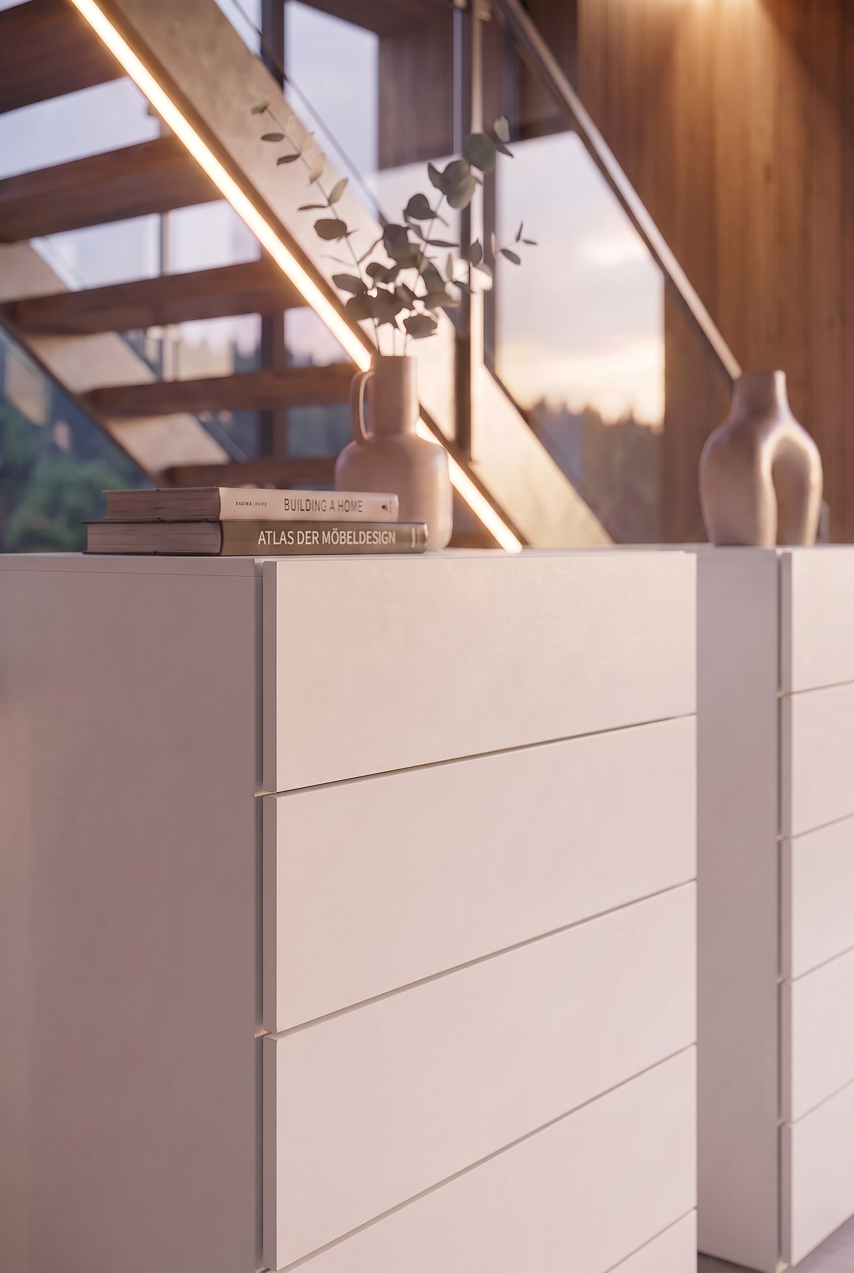 Detail einer weißen Kommode mit Design-Büchern und einer Keramikvase im warmen Sonnenlicht.