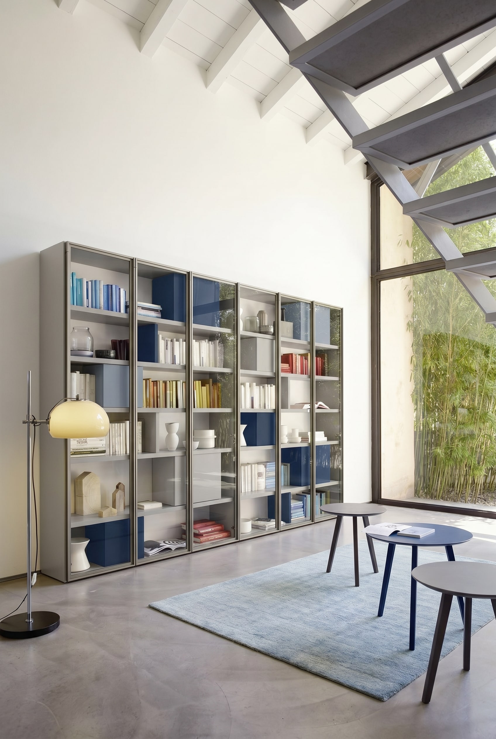 Lichtgraues maßgefertigtes Bücherregal mit minimalen Fachabständen und integrierten blauen Boxen