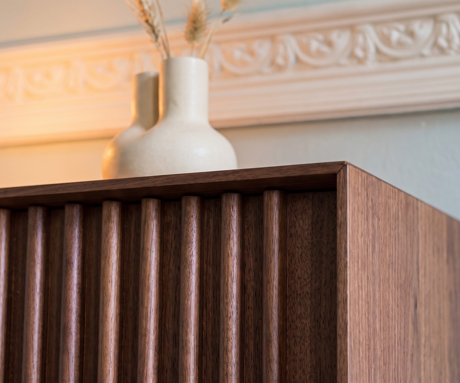 Design Sideboard al2 ka-bera 003 A aus Walnuss mit Holz-Lamellen, Detailansicht mit Vase im Wohnzimmer.