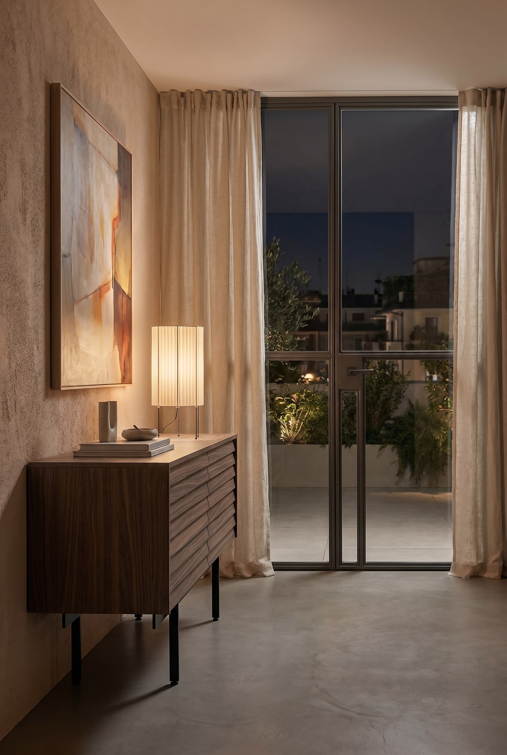 Gemütliches Schlafzimmer mit niedrigem Holz-Sideboard und Tischleuchte mit plissiertem Stoffschirm in Beige bei warmem Licht