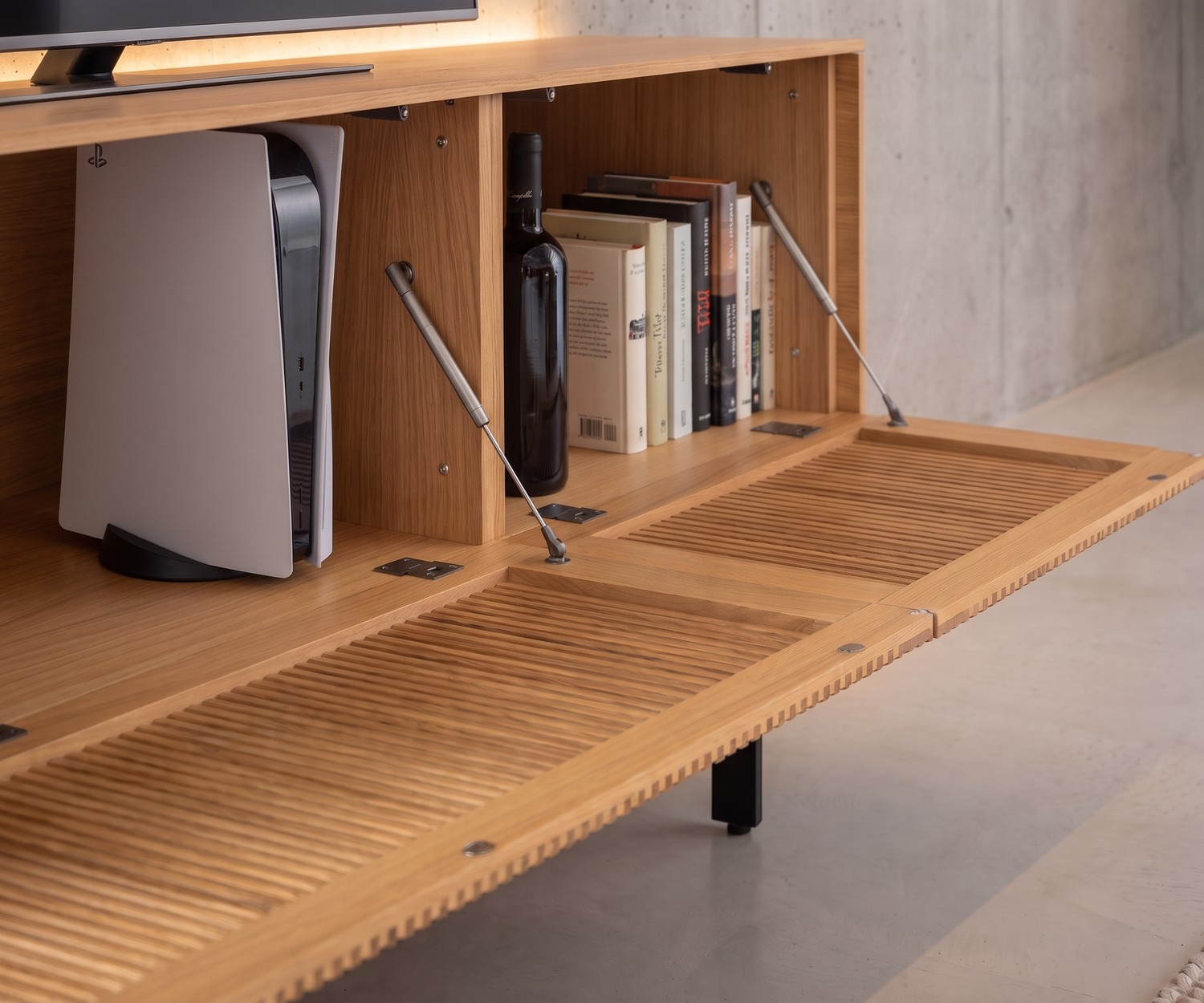 Punt Malmö TV Lowboard aus Eiche mit Lamellen-Klapptür und Stauraum für Konsole und Bücher im modernen Wohnzimmer.