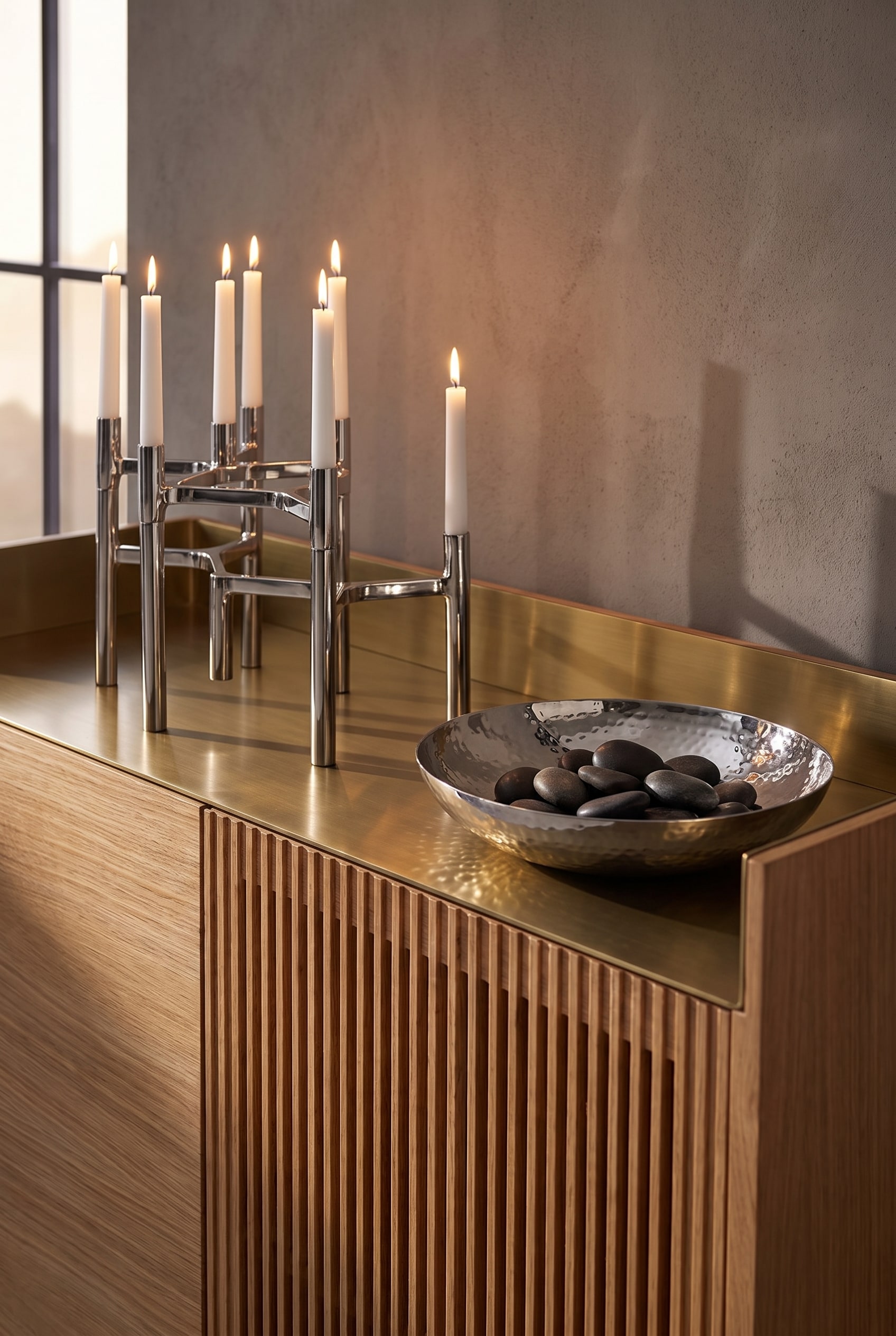 Sideboard aus hellem Eichenholz mit Lamellenfront und einer Aluminium-Deckplatte, best&uuml;ckt mit k&uuml;hlen, silbernen Kerzenst&auml;ndern und einer Edelstahlschale