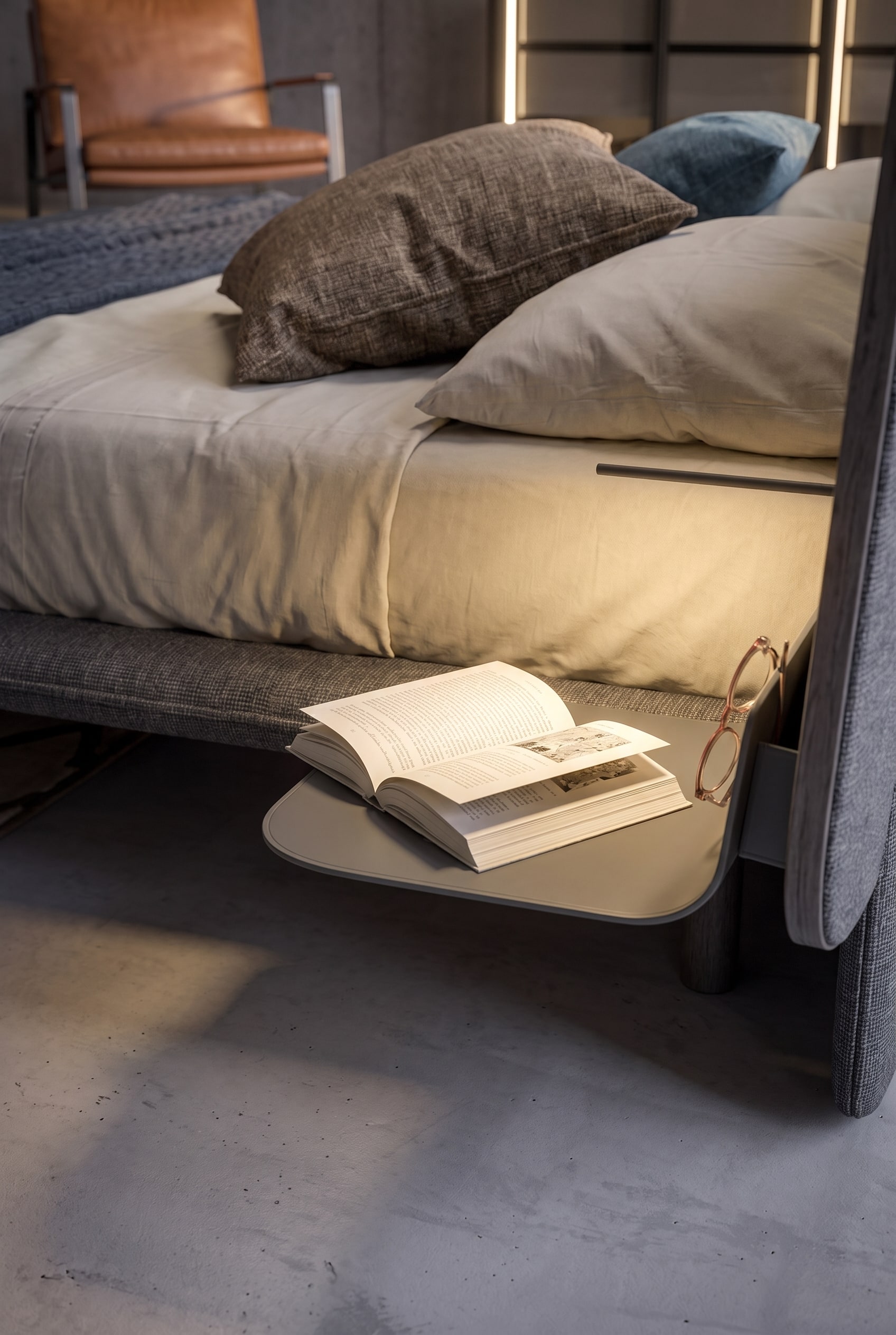 Freischwebende Nachttisch-Ablage aus Metall, montiert am Bettkopfteil, mit einem aufgeschlagenen Buch und einer Brille.