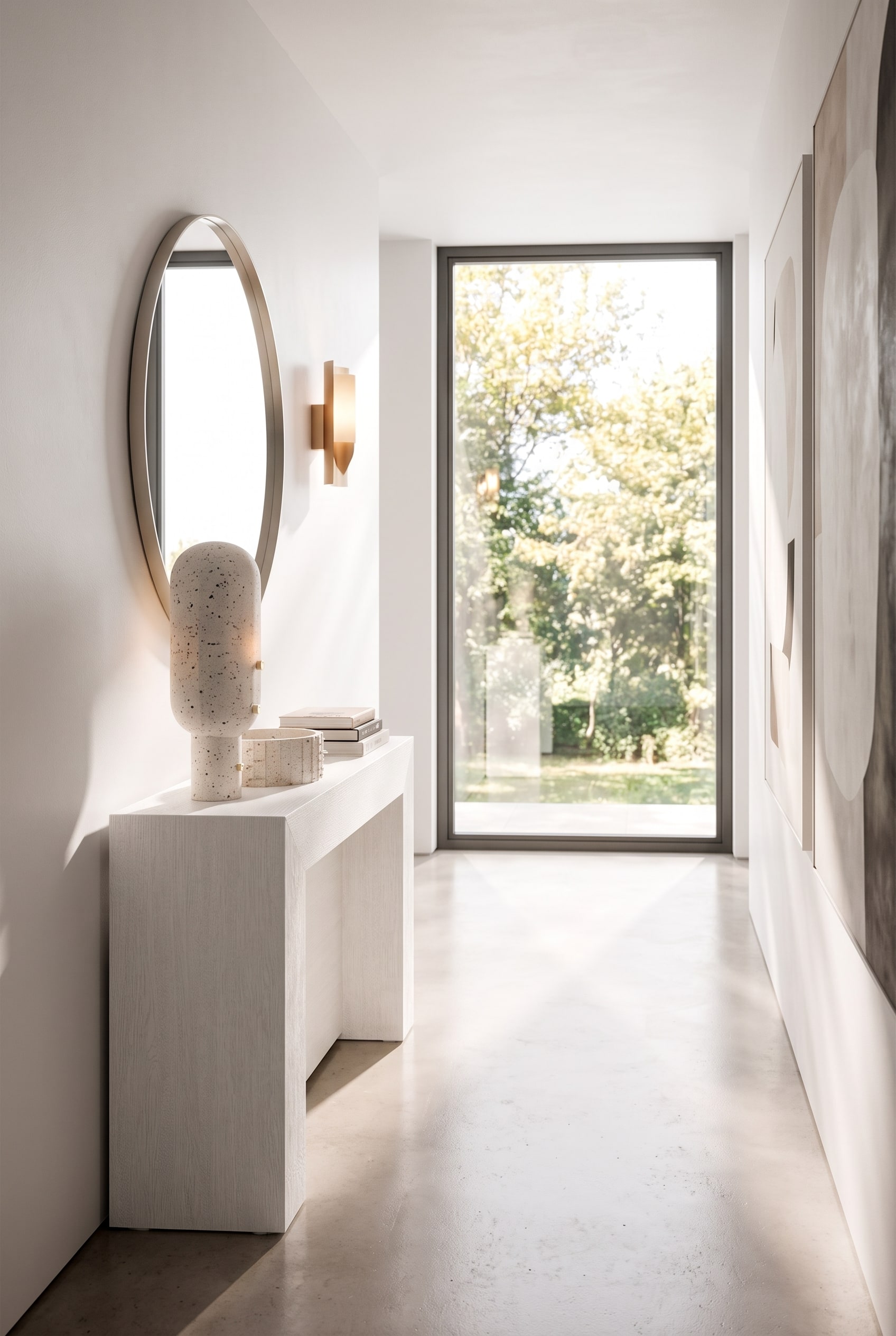 Schmaler Flur mit einer extrem flachen wei&szlig;en Konsole, dar&uuml;ber ein runder Wandspiegel und eine minimalistische Wandleuchte