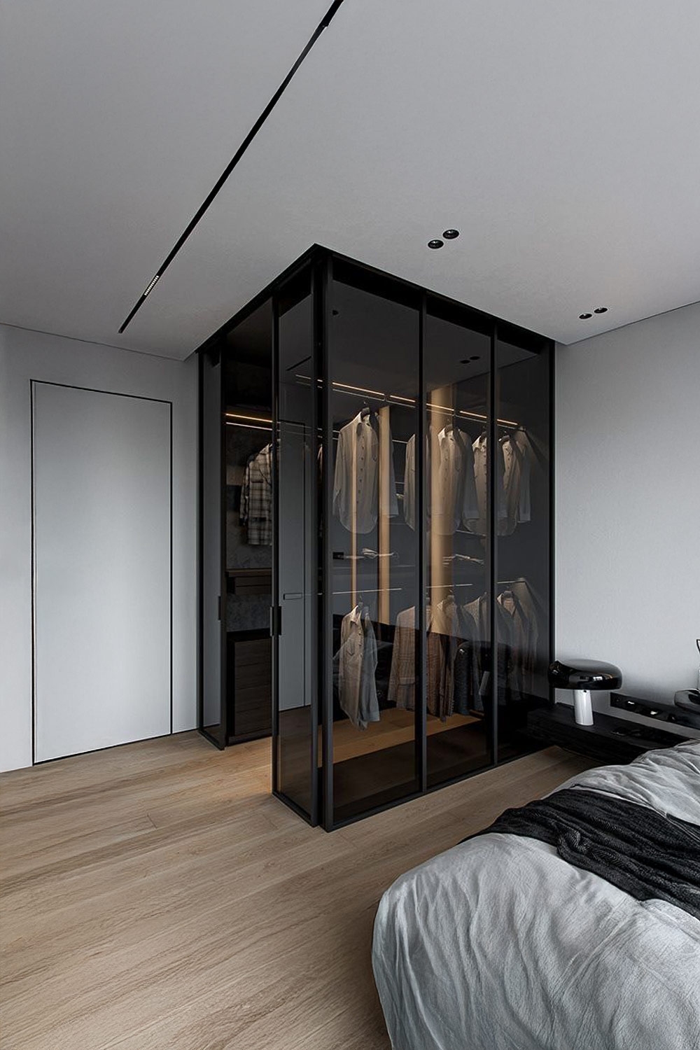 dunkler-kleiderschrank-mit-transparenten-tueren-neben-einem-bett