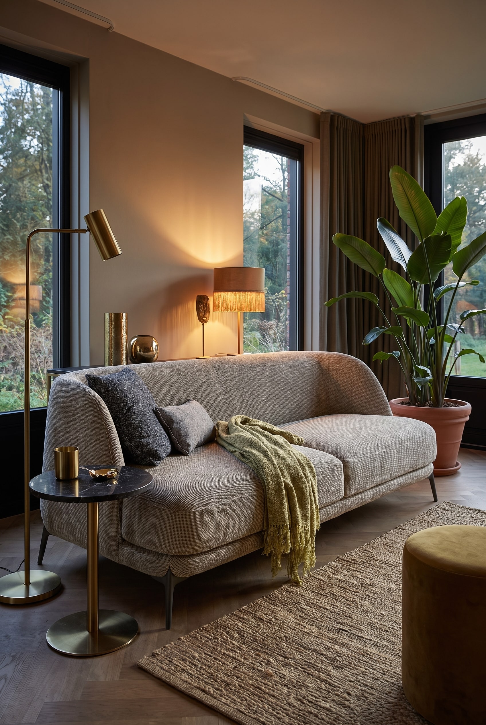 Wohnzimmer im Boho-Glamour-Stil mit einem organisch geformten Samtsofa in warmem Farbton, ergänzt durch Messing-Details und große Pflanzen